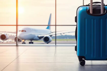 blue suitcase is sitting front w बढ़ते यात्री यातायात ने एयरलाइन संघर्ष को तेज कर दिया है क्योंकि समूह और सामान्य प्रबंधन प्रवेश समिति ने लगातार देरी से प्रमुख वफादारी जोखिमों का खुलासा किया है